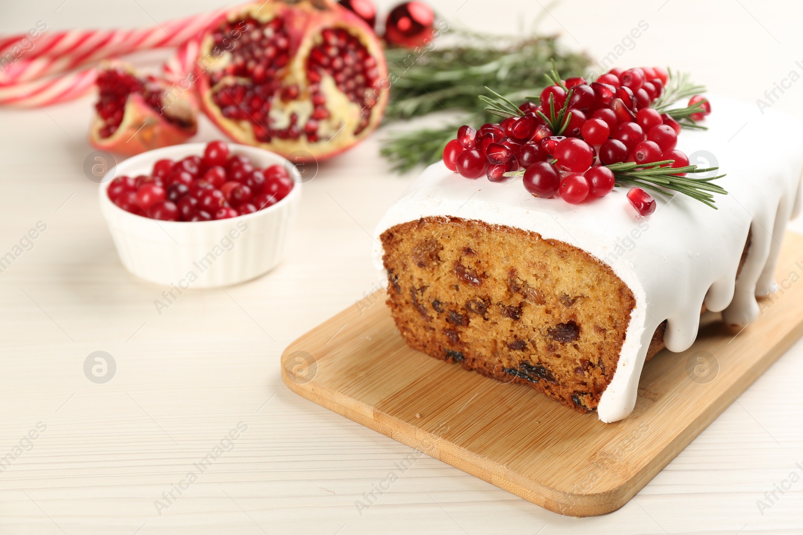 Photo of Traditional classic Christmas cake decorated with cranberries, pomegranate seeds and rosemary on white wooden table