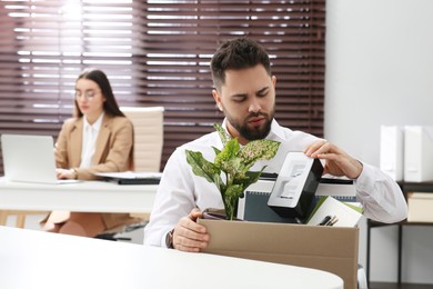 Photo of Dismissed man packing personal stuff into box in office