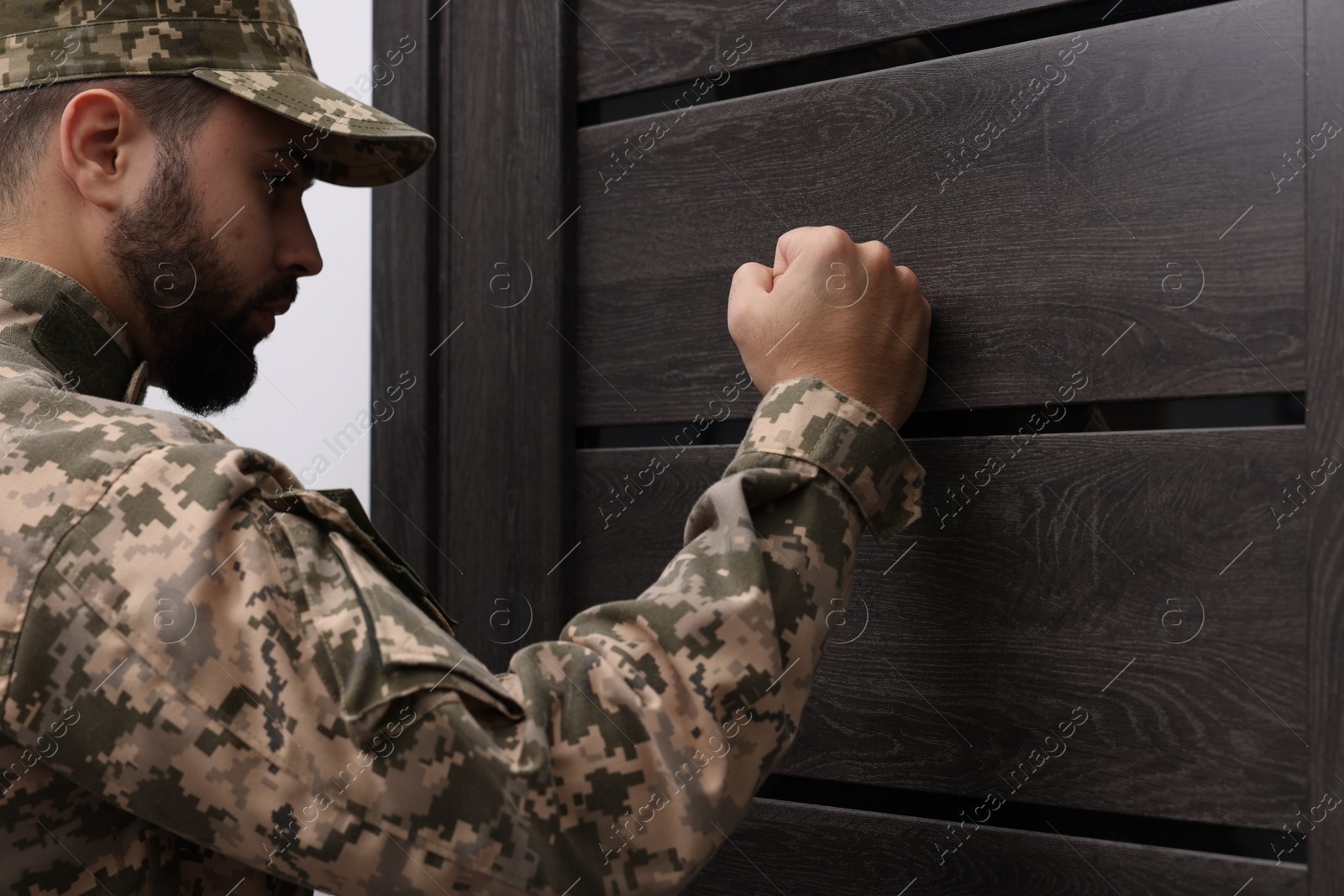 Photo of Military commissariat representative knocking on wooden door