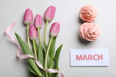 Photo of 8 March greeting card design with tulips and cupcakes on light grey background, flat lay. International Women's day