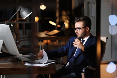 Photo of Concentrated young businessman working in office alone at night