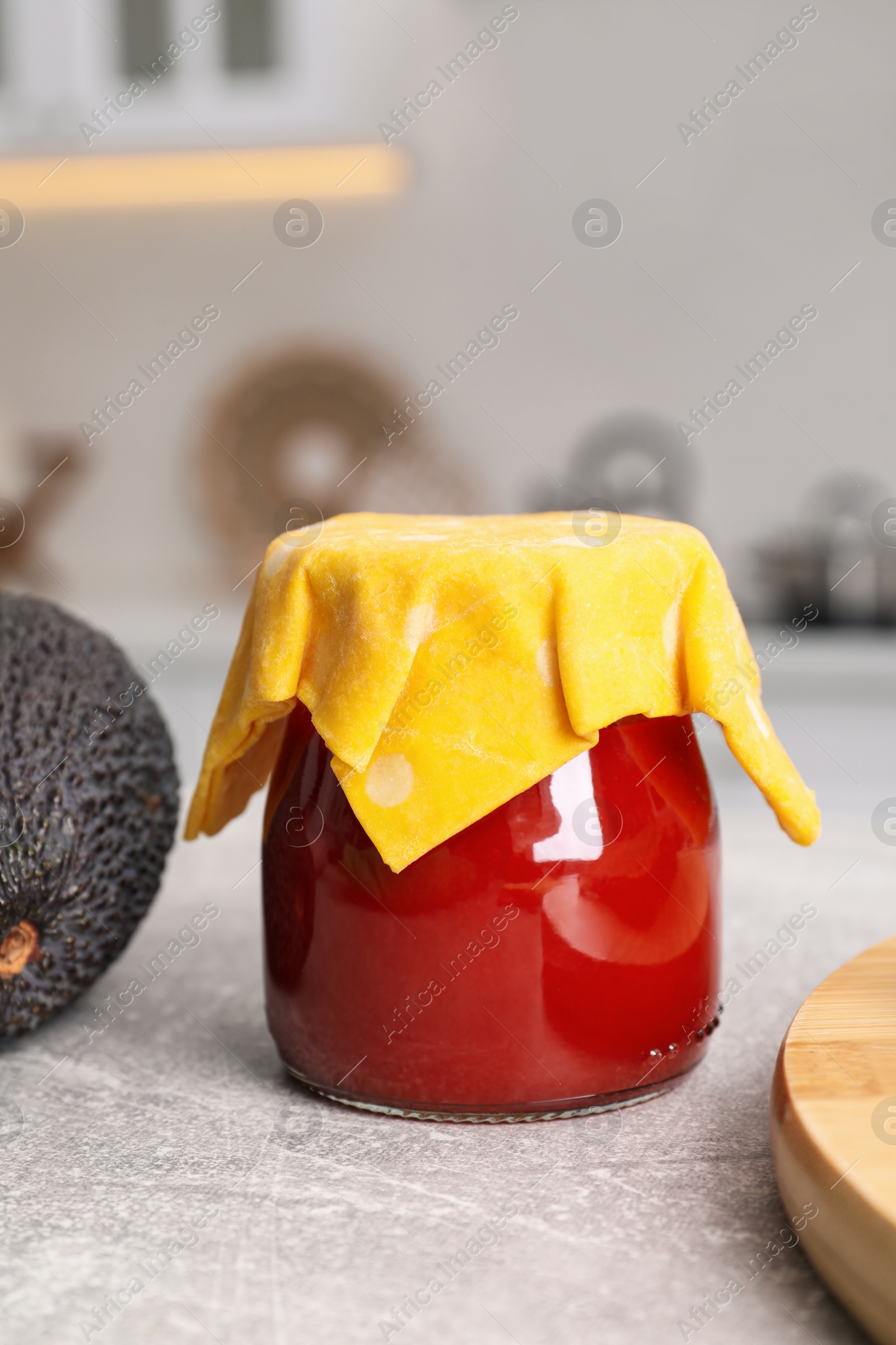 Photo of Jar of tomato paste covered with beeswax food wrap on light grey table