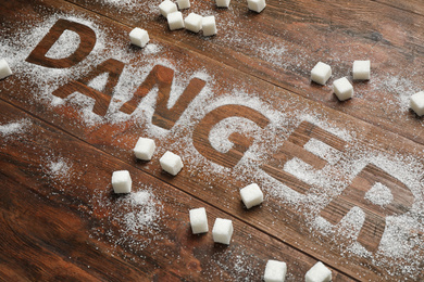 Composition with word DANGER and sugar on wooden table