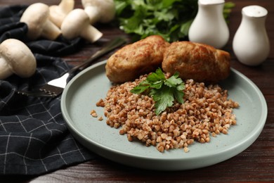 Photo of Tasty buckwheat with fresh parsley and cutlets on wooden table