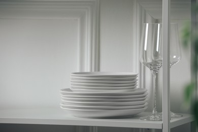 Photo of Stacked clean dishes and glasses on table indoors