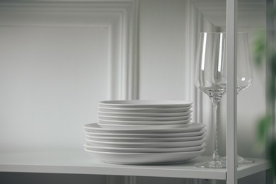 Stacked clean dishes and glasses on table indoors