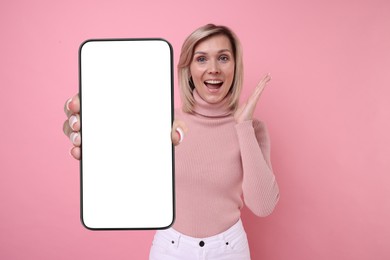 Woman showing mobile phone with blank screen on pink background. Mockup for design