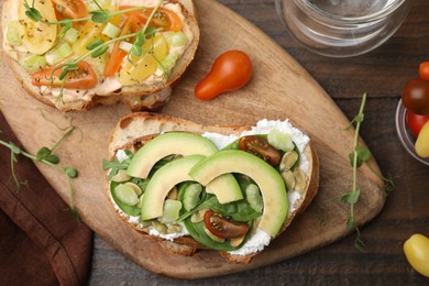 Photo of Tasty vegan sandwiches with vegetables on wooden table, flat lay