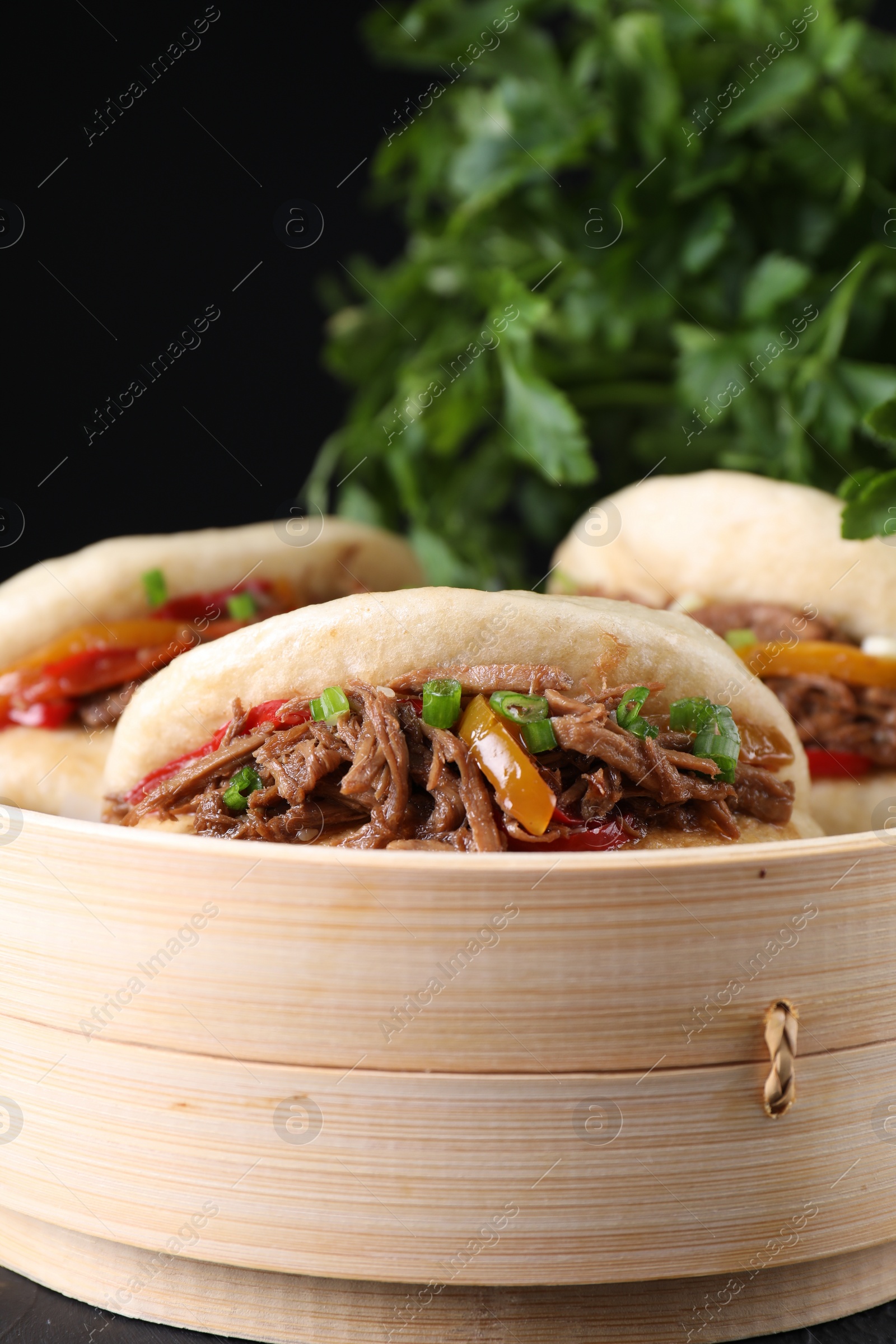 Photo of Delicious gua bao in bamboo steamer on table, closeup