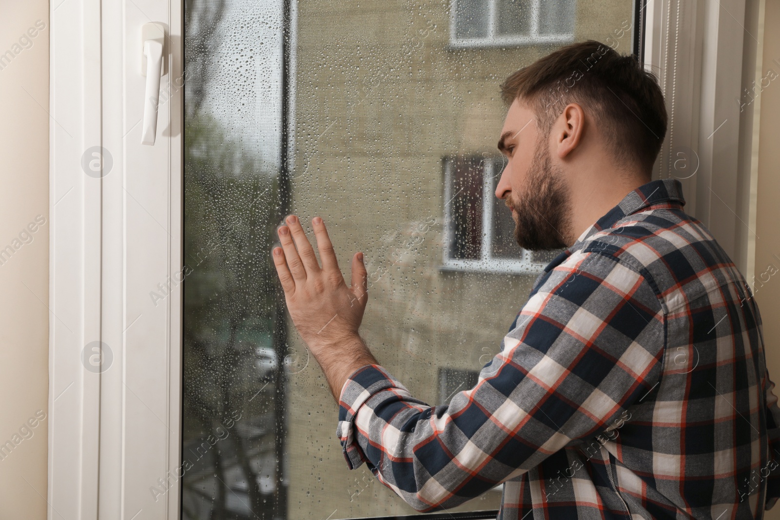 Photo of Depressed young man near window at home