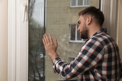 Photo of Depressed young man near window at home