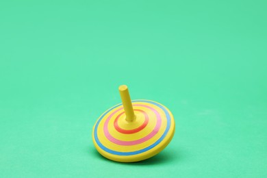 Photo of One bright spinning top on green background, space for text. Toy whirligig