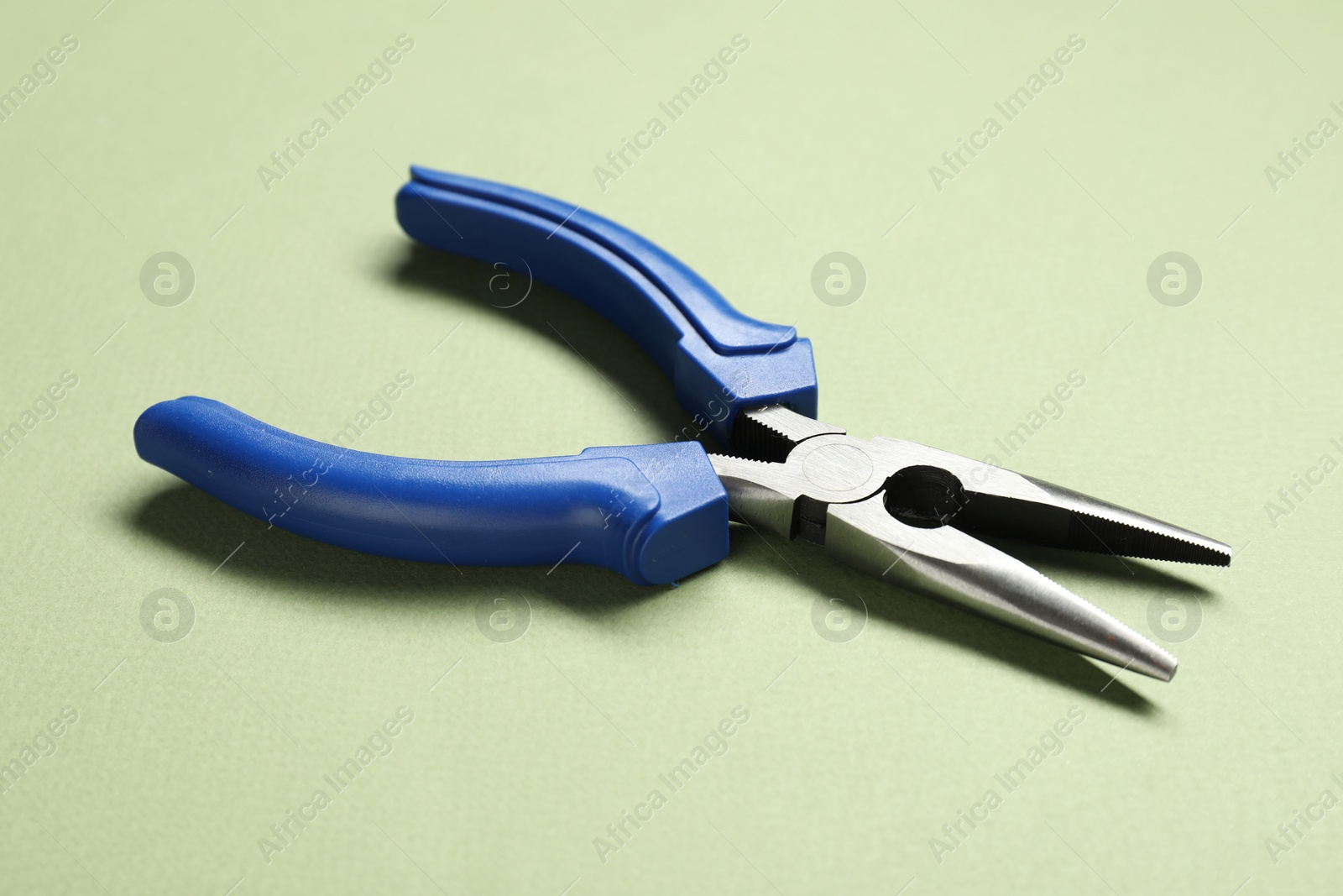 Photo of Needle nose pliers on olive background, closeup