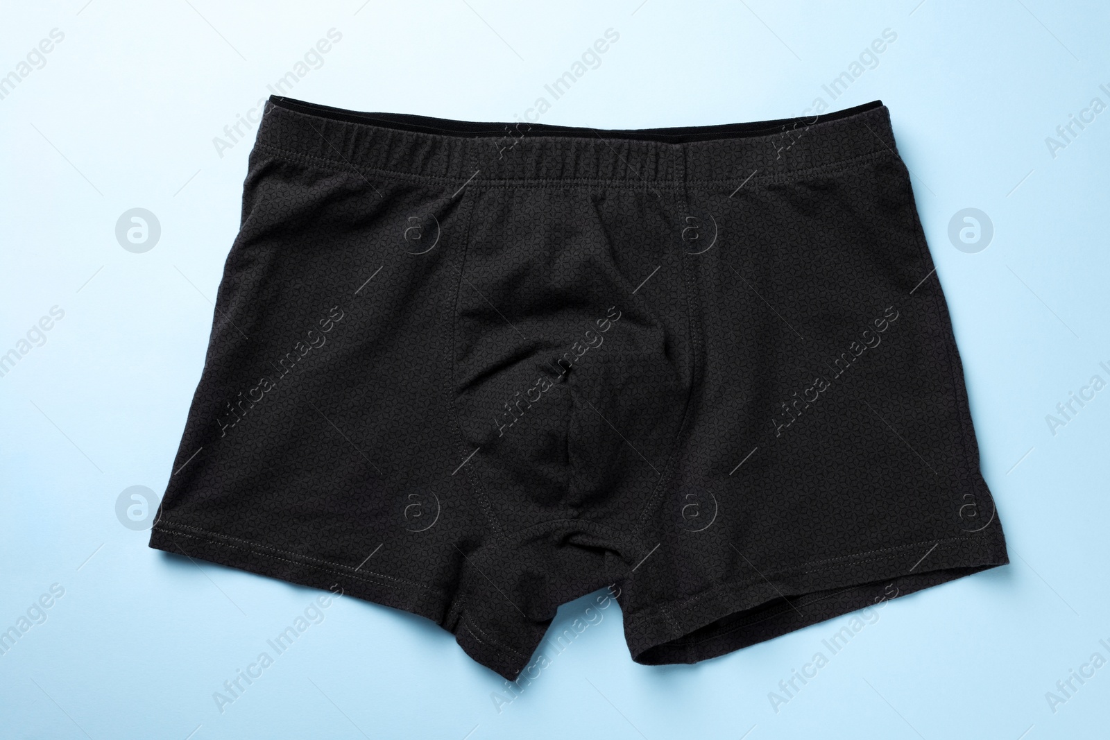 Photo of Black man's underwear on light blue background, top view