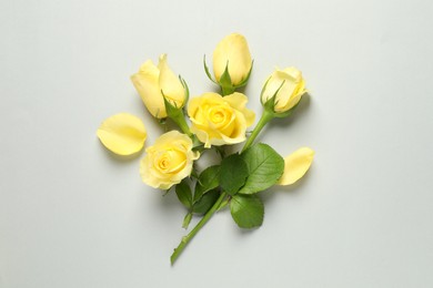 Photo of Beautiful yellow roses and petals on light grey background, flat lay