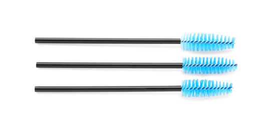 Photo of Three brushes for eyelashes on white background, top view