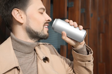 Happy man drinking from tin can outdoors. Space for text