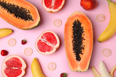 Photo of Flat lay composition with condoms and exotic fruits on pink background. Erotic concept