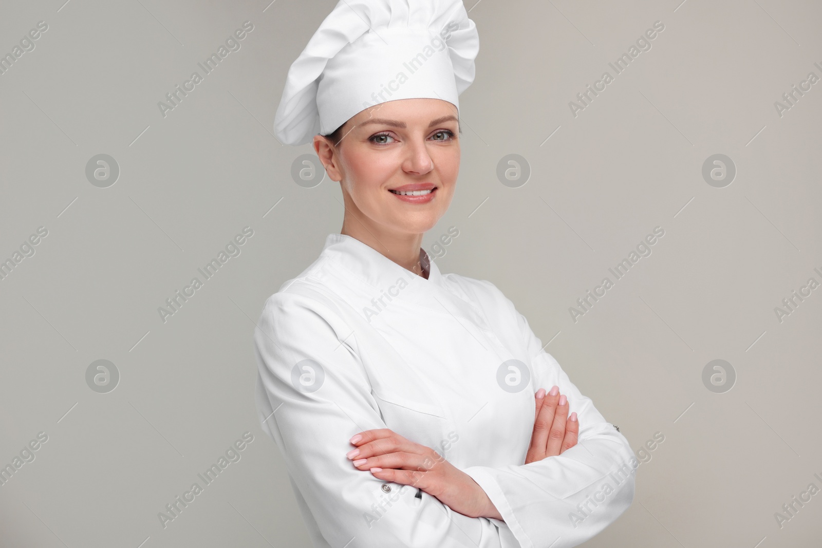 Photo of Happy chef in uniform on grey background