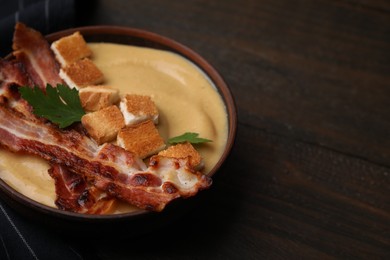 Photo of Delicious lentil soup with bacon and parsley in bowl on wooden table, closeup. Space for text