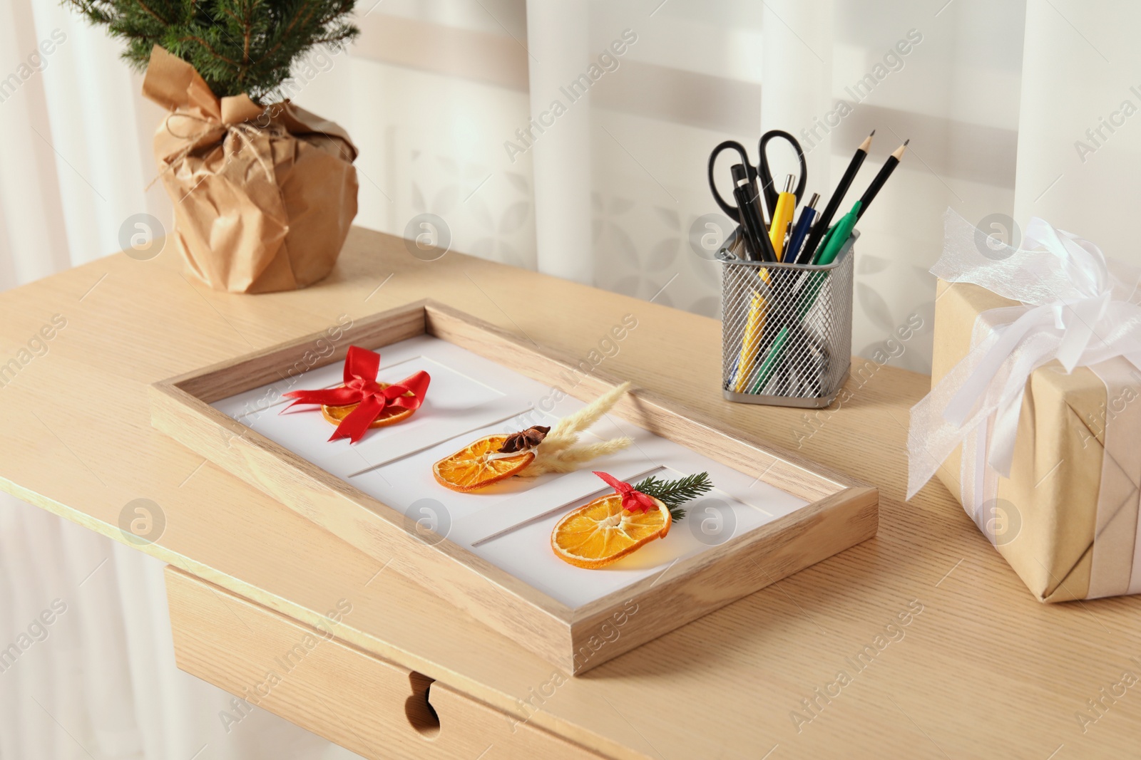 Photo of Beautiful frame with decorated dry orange slices on wooden table indoors