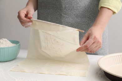 Photo of Making tasty baklava. Woman with dough at table, closeup