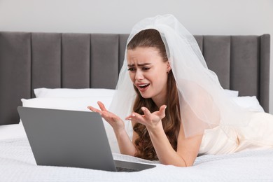 Emotional bride with laptop on bed in bedroom