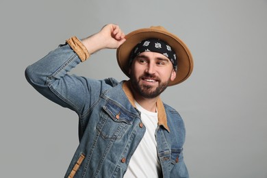 Photo of Fashionable young man in stylish outfit with bandana on grey background