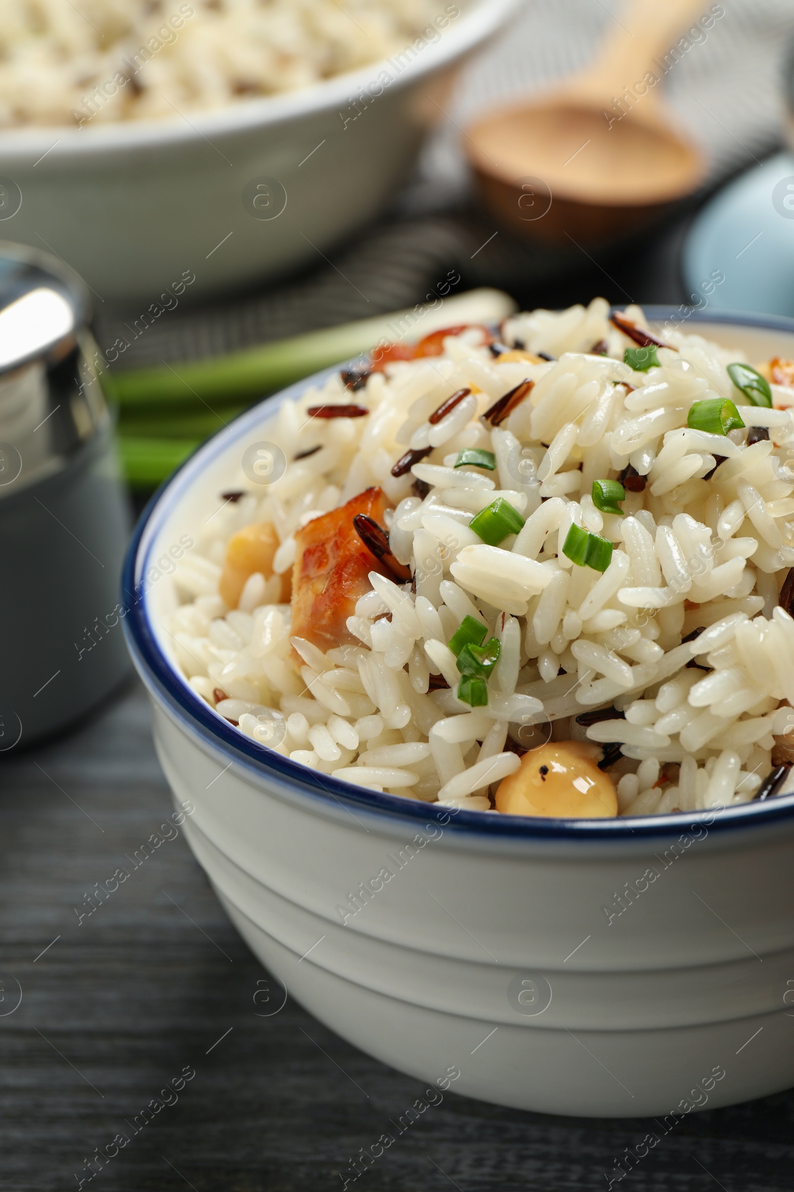 Photo of Delicious rice pilaf with chicken on black wooden table, closeup