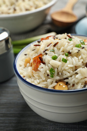 Delicious rice pilaf with chicken on black wooden table, closeup