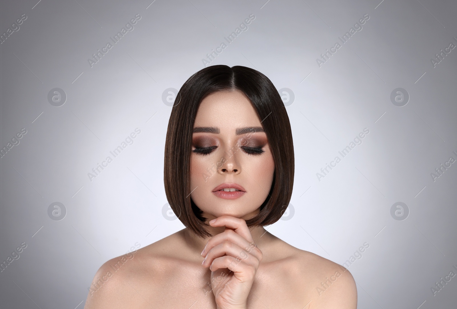 Image of Portrait of pretty young woman with brown hair on grey background