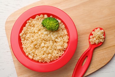 Bowl of tasty pasta with broccoli on white wooden table, top view