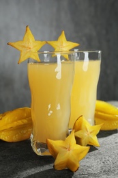 Delicious carambola juice and fresh fruits on grey table