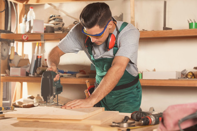 Professional carpenter working with jigsaw at workbench