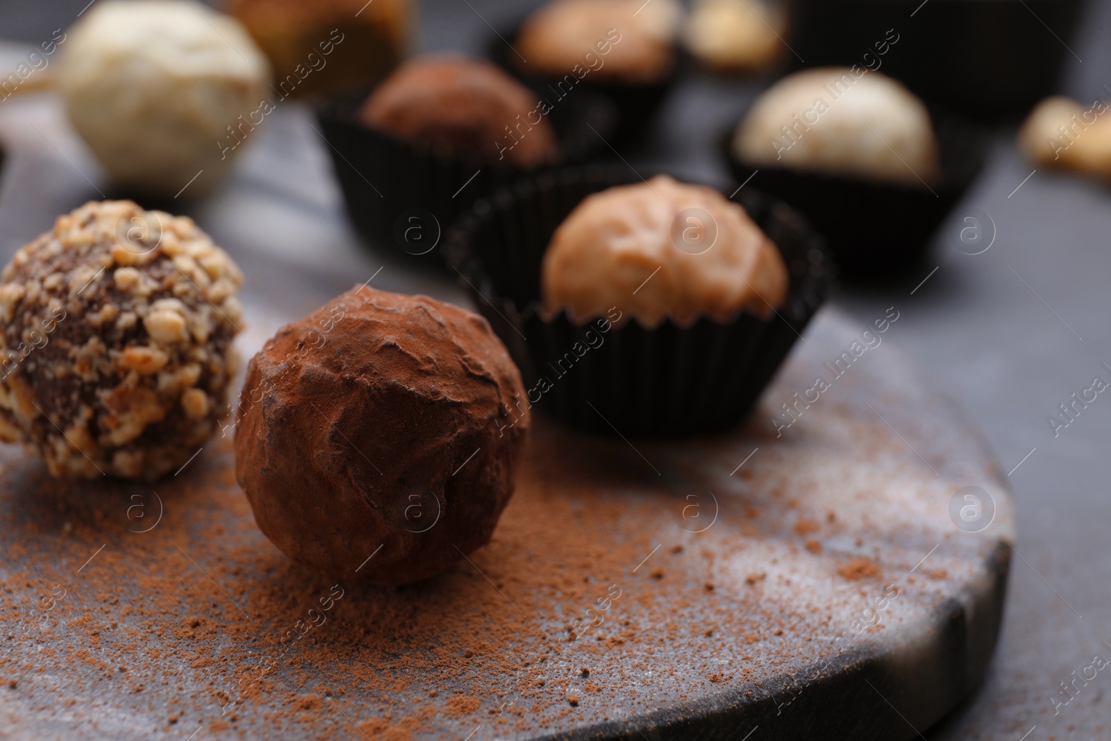 Photo of Different tasty chocolate candies on marble board, closeup