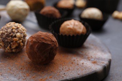 Photo of Different tasty chocolate candies on marble board, closeup