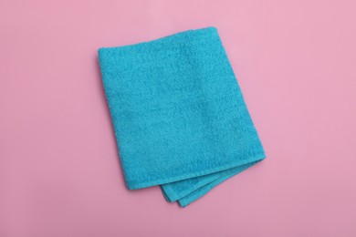 Folded light blue beach towel on pink background, top view