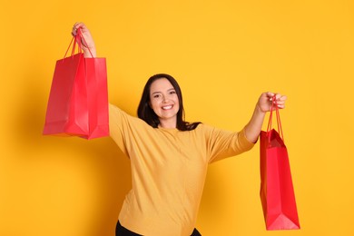 Photo of Beautiful overweight woman with shopping bags on yellow background