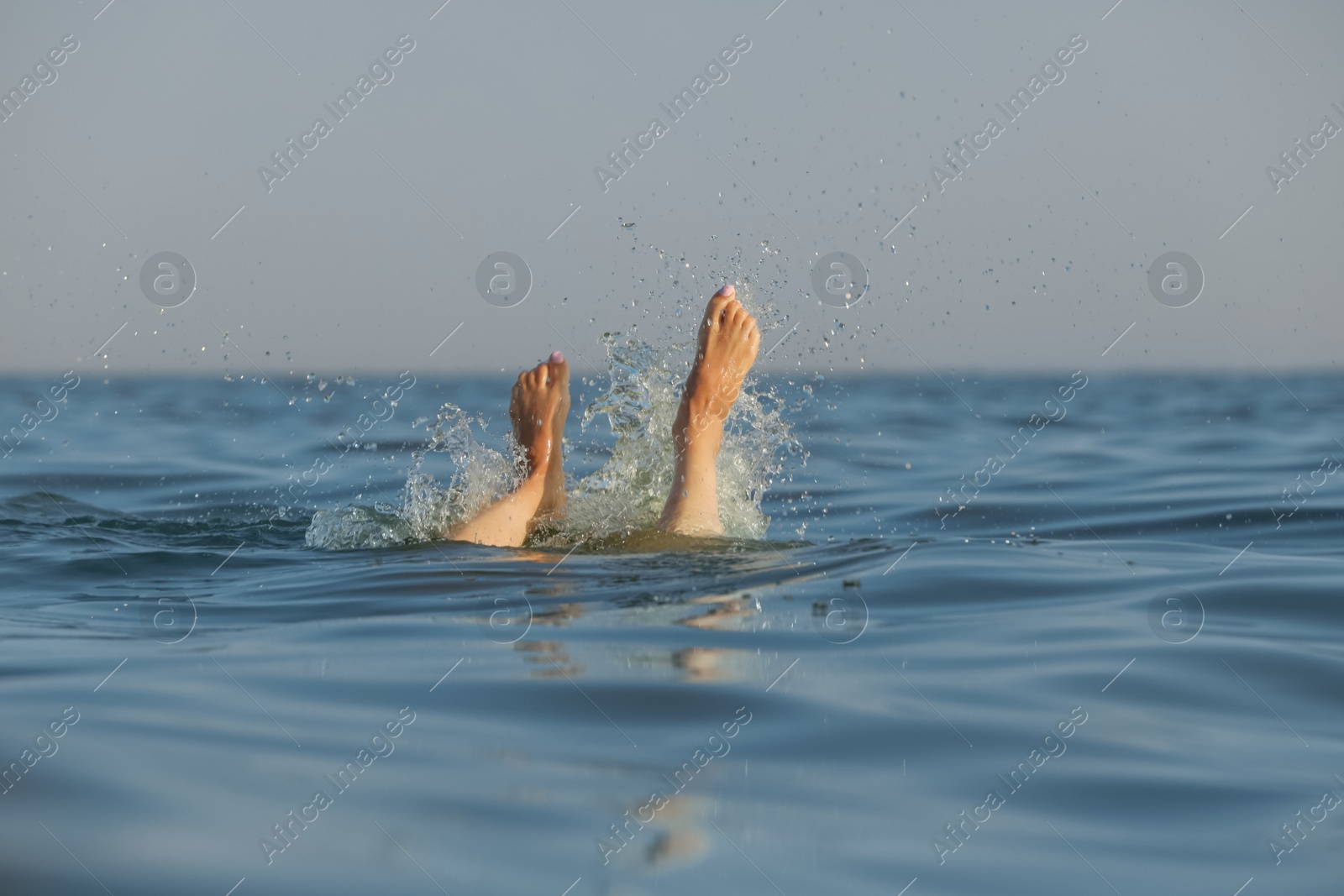 Photo of Drowning woman's legs sticking out of sea