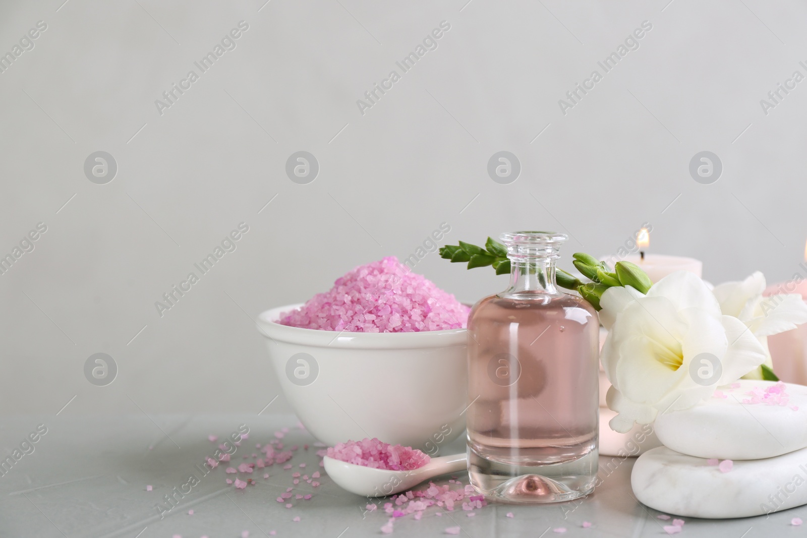 Photo of Beautiful composition with spa stones and essential oil on light grey table, space for text