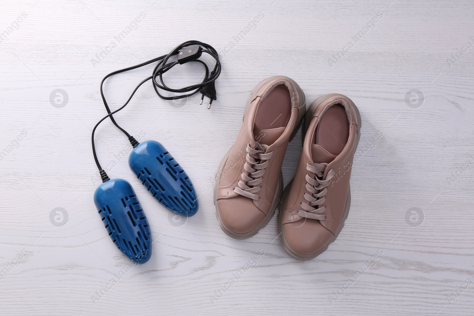 Photo of Shoes and electric dryer on white wooden background, flat lay