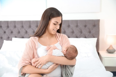 Photo of Young woman with her newborn baby in bedroom
