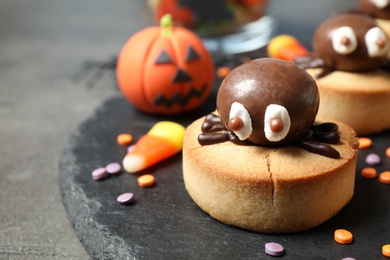 Photo of Delicious biscuits with chocolate spiders on grey table, closeup. Halloween celebration