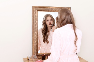 Young woman applying makeup near mirror in dressing room