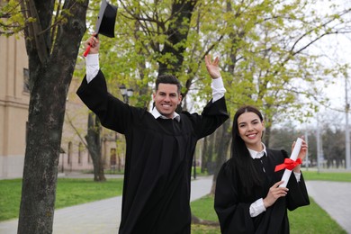 Photo of Happy students with diplomas after graduation ceremony outdoors