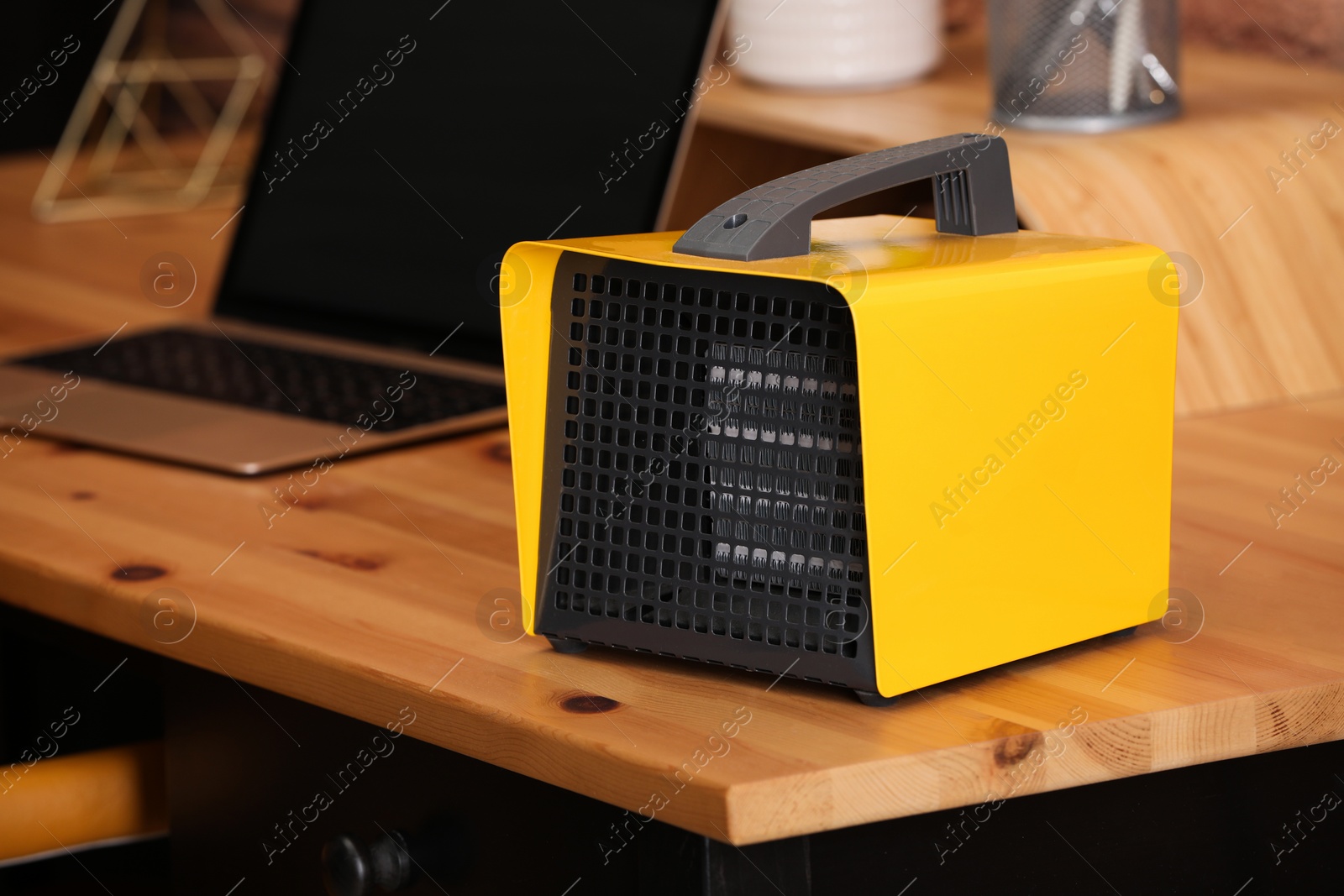 Photo of Modern electric heater near laptop on wooden table in office