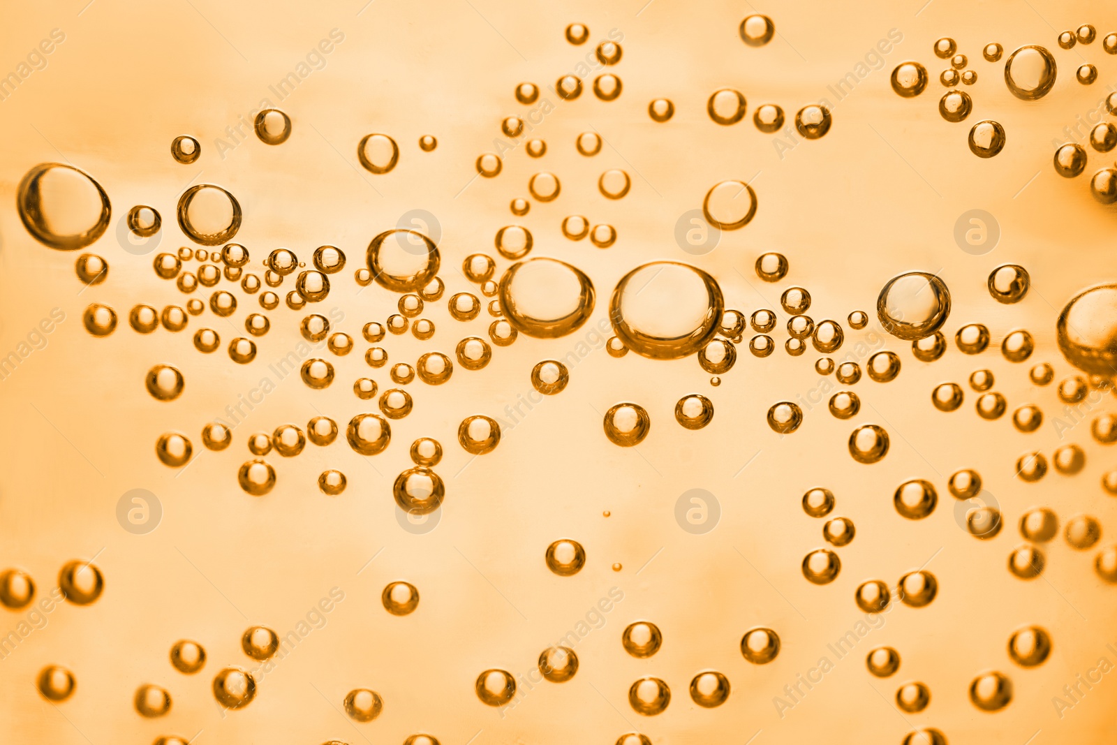 Image of Soda water with bubbles of gas, closeup. Toned in orange