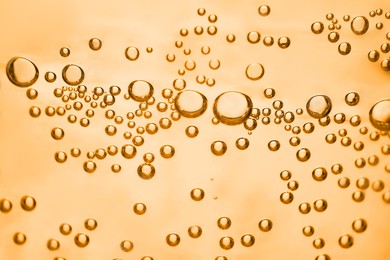 Soda water with bubbles of gas, closeup. Toned in orange