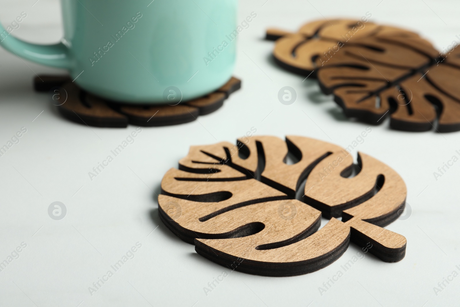 Photo of Leaf shaped wooden cup coasters on white table