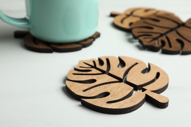 Leaf shaped wooden cup coasters on white table